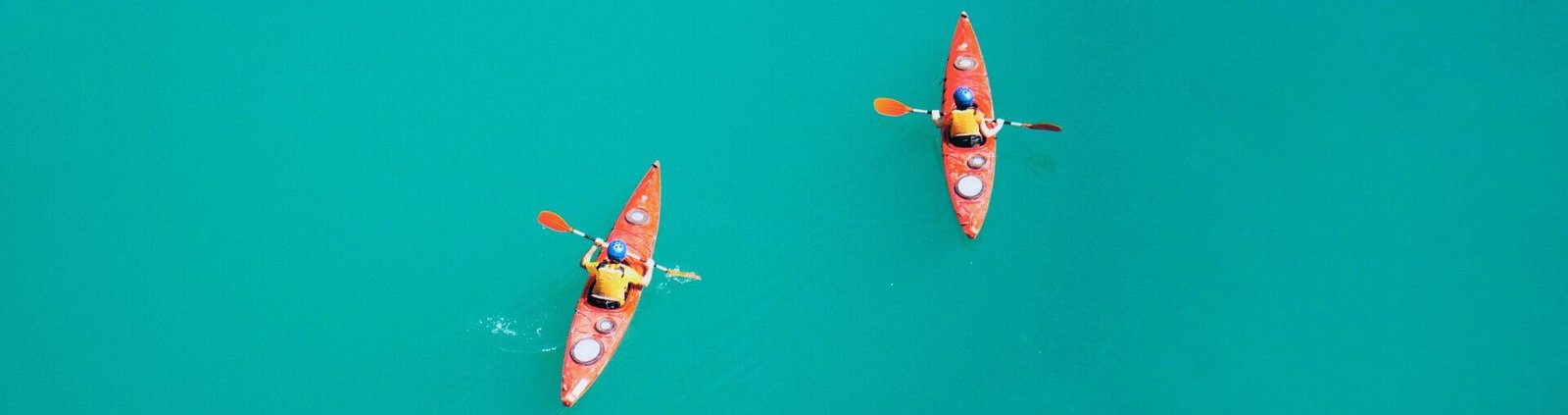 2 kayakistes avec gilet de sauvetage pagaient sur une eau bleue turquoise