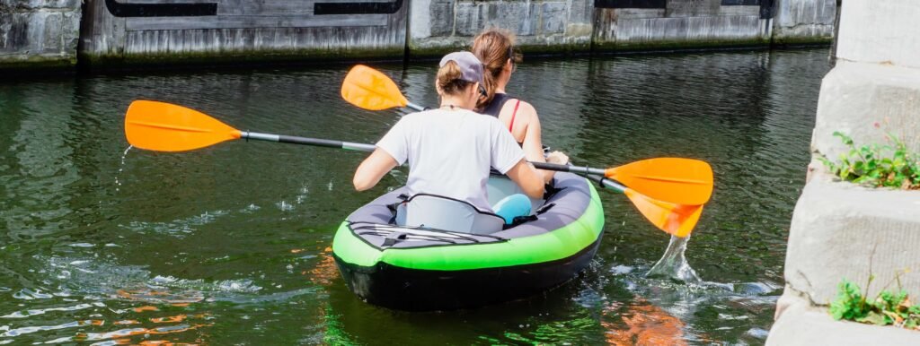 Deux femmes, de dos, naviguant sur un canoë kayak gonflable noir et vert