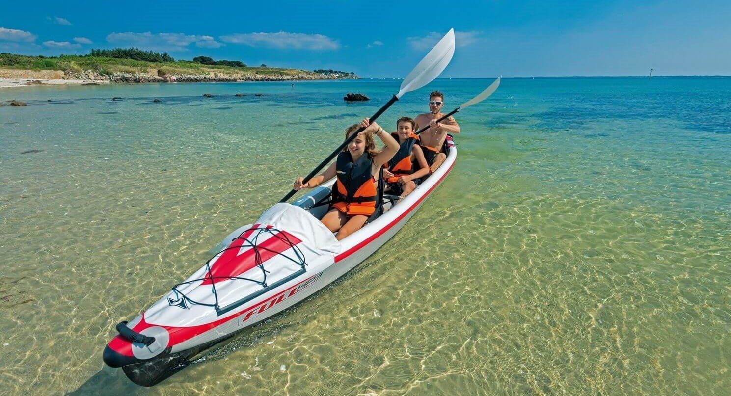 kayak gonflable 3 places accostant sur une plage avec un couple et un enfant