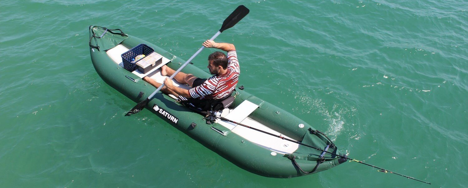 Homme ramant sur un kayak gonflable. Une canne à pêche est posée dans le bateau vert foncé