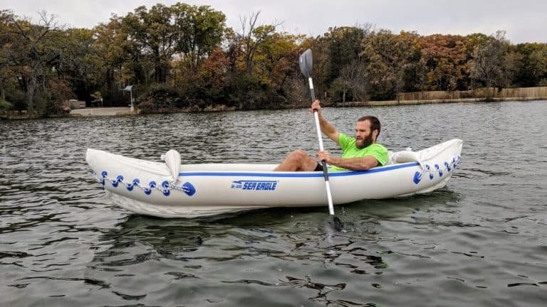 Homme sur un lac, pagayant dans son kayak gonflable