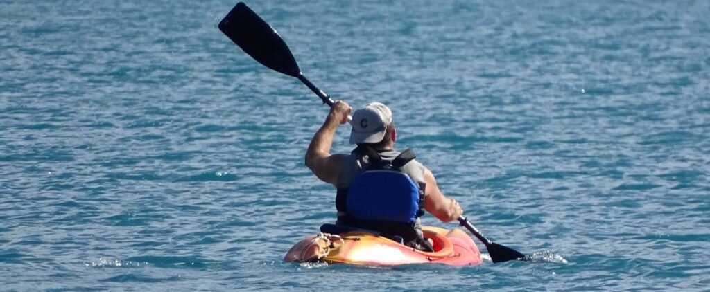 Homme vue de dos pagayant dans un kayak gonflable