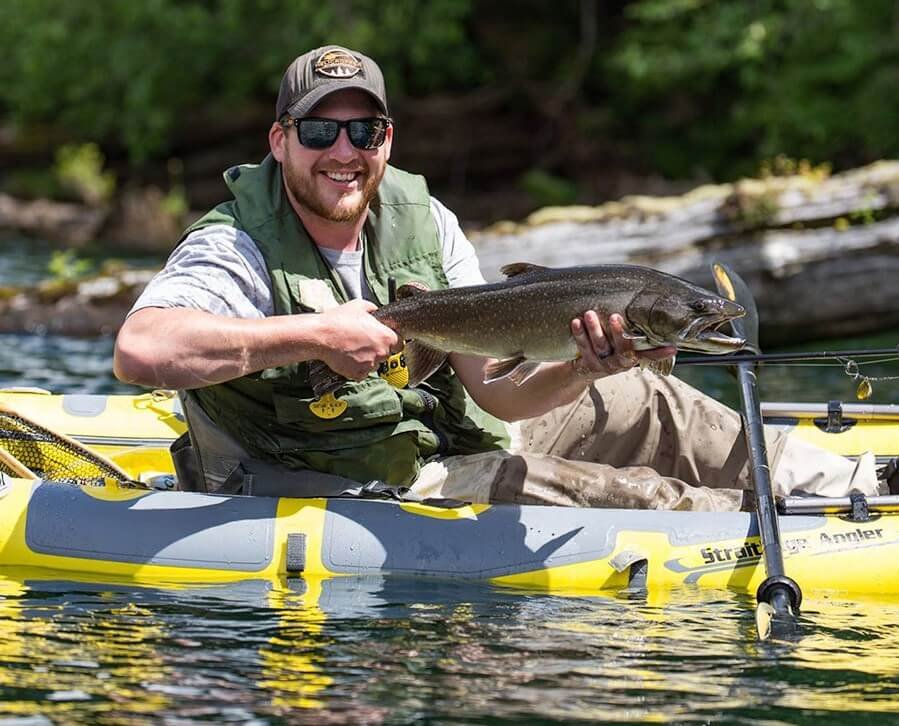 Homme à bord d'un kayak gonflable ayant pêcher un poisson